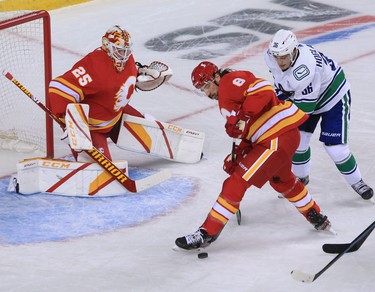 The Calgary Flames’ Christopher Tanev and the Vancouver Canucks’ Nils Hoglander wrestle for the puck in front of goalie Jacob Markstrom during the Calgary Flames NHL home opener on Saturday, January 16, 2021. 
Gavin Young/Postmedia