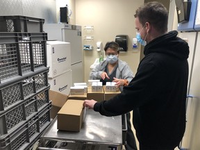 Sheila Mondragon and Robbie Shields (right), with AHS Supply Management, accept the first delivery of the Moderna COVID-19 vaccine in Calgary on Tuesday, Dec. 29, 2020.