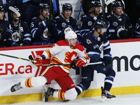 The Calgary Flames’ Juuso Valimaki and Winnipeg Jets’ Trevor Lewis collide along the boards in Winnipeg on Thursday, Jan. 14, 2021.