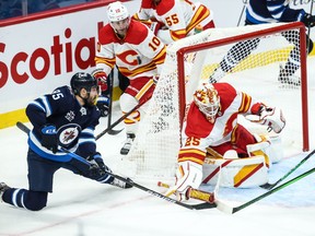 Calgary Flames goalie Jacob Markstrom clears the puck away from Winnipeg Jets forward Matthieu Perreault during the third period at Bell MTS Place in Winnipeg on Thursday, Jan. 14, 2021.