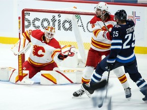 Calgary Flames goalie Jacob Markstrom (25) makes a save as defenceman Chris Tanev blocks out Winnipeg Jets forward Paul Stasny during the second period at Bell MTS Place in Winnipeg on Thursday, Jan. 14, 2021.