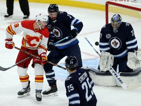 Calgary Flames forward Matthew Tkachuk (left) tips a shot past Winnipeg Jets goaltender Connor Hellebuyck with Tucker Poolman defending during NHL action in Winnipeg on Thursday, Jan. 14, 2021.