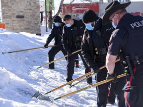 Members of the Calgary Police Service rake snow in search of evidence at the scene of a suspicious death in the parking lot of Mazaj Lounge and Restaurant on Macleod Trail on Saturday, February 20, 2021. Azin Ghaffari/Postmedia