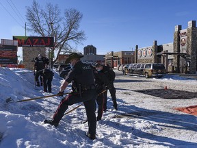 Members of Calgary Police Services rake the snow for evidence at the scene of a suspicious death at the parking lot of Mazaj Lounge and Restaurant on Macleod Trail on Saturday, Feb. 20, 2021.