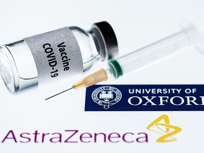 This file illustration taken in Paris on Nov. 23, 2020 shows a syringe and a vial reading "COVID-19 Vaccine" next to AstraZeneca company and University of Oxford logos.