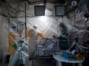In this file photo taken Aug. 15, 2018, three medical workers check on an Ebola patient in a Biosecure Emergency care Unit, in Beni, Democratic Republic of the Congo.