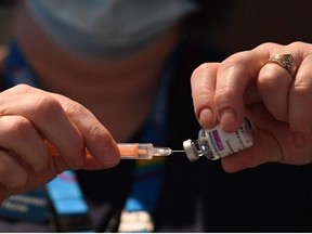 A healthcare professional draws up a dose of AstraZeneca/Oxford Covid-19 vaccine in a syringe at the vaccination centre set up at Chester Racecourse, in Chester, northwest England, on February 15, 2021.