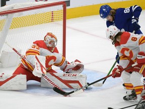 Calgary Flames goalie David Rittich makes a save as defenceman Christopher Tanev battles with Toronto Maple Leafs forward William Nylander on Monday night at Scotiabank Arena in Toronto.