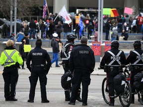 Peace officers and Calgary Police watch protesters gathered to rally against pandemic restrictions outside city hall on Jan. 6, 2021.