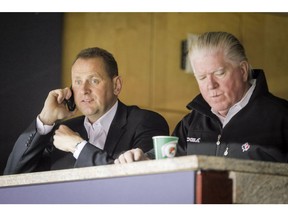 Calgary Flames GM Brad Treliving watches a Flames practice next to Brian Burke, who was the team's president of hockey operations in this photo from October 2014.