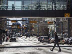 A pedestrian crosses a street in downtown Calgary on a sunny day on Thursday, March 4, 2021.