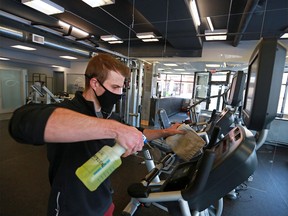Urban Athlete Fitness Studio owner Kohl Kehler sanitizes equipment in preparation for the lifting of some pandemic restrictions on fitness facilities on Monday, March 1, 2021.