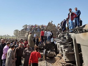 People gather around the wreckage of two trains that collided in the Tahta district of Sohag province on March 26, 2021.
