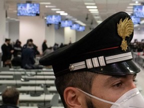 In this Jan. 13, 2021 file photo, an Italian Carabinieri police officer wearing a face mask stands guard at a special courtroom in Lamezia Terme, Calabria.