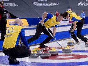 Team Wild Card 2 lead Ben Hebert and second John Morris bring a stone into the house as skip Kevin Koe watches during a game against Saskatchewan at the Tim Hortons Brier at WinSport’s Markin MacPhail Centre in Calgary on Wednesday, March 10, 2021.