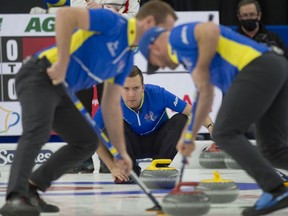 Alberta skip Brendan Bottcher crouches in the rings as lead Karrick Martin and third Darren Moulding brush the stone into the house Saturday at the Brier.