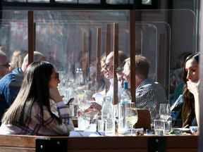 Plexiglass divides guests at the Lulu Bar who are enjoying lunch on the patio along 17th Ave. SW. Friday, March 12, 2021.