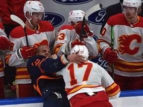 Oilers blueliner Darnell Nurse and Flames forward Milan Lucic mix it up along the boards during NHL action at Rogers Place in Edmonton late Saturday night.