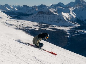 Skier makes turns down the Divide with Mount Assiniboine in the background at Banff's Sunshine Village.