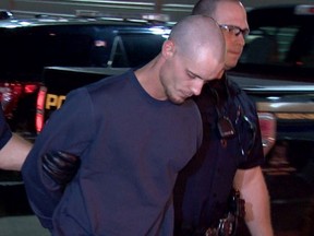 Officers lead suspect Dustin Duthie into the Calgary Police Service arrest processing unit late Tuesday night, Dustin Duthie is the lone suspect in slaying of Taylor Toller, Shawn Boshuck and Alan Pennylegion. Photo courtesy of CBC Calgary