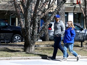 Masked pedestrians are seen walking along 17 Ave S.W. on Friday, April 2, 2021.