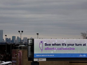 The Edmonton skyline is visible behind a digital billboard displaying a COVID-19 vaccination advertisement on Thursday March 25, 2021.