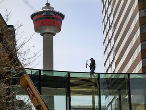 A man cleans the outside of a Plus-15 crossing over Centre St. in downtown Calgary on Saturday, April 3, 2021.