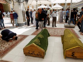 A man prays next to the coffins of people who were killed in a fire at a hospital in southeastern Baghdad that had been equipped to house COVID-19 patients, in Najaf, Iraq, Sunday, April 25, 2021.
