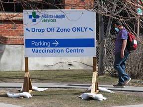 Calgarians walk past the sign marking the COVID-19 vaccination site at the Richmond Road Diagnostic and Treatment Centre on Wednesday, April 7, 2021.