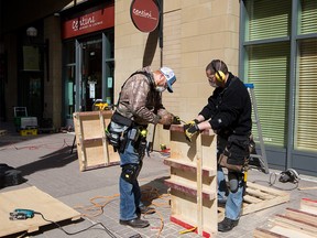 Brady Anderson, left and Jay Matticks build the outdoor patio area at Centini Restaurant in downtown Calgary on Tuesday, April 13, 2021. Current COVID-19 restrictions only allow for outdoor in-person dining.