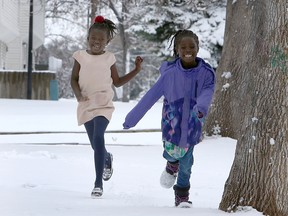 Seven year-old Abuk Garng (R) and her best friend six year-old Arek Kuot are seen embracing the winter weather in front of their home along 8th Ave. SW. Sunday, April 18, 2021.