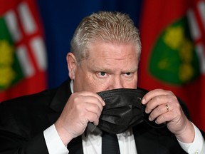 Ontario Premier Doug Ford puts his mask on after speaking at a press conference at Queen's Park, in Toronto, Friday, April 16, 2021.