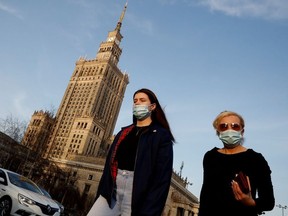 People wearing protective masks amid the outbreak of coronavirus disease (COVID-19) walk in front of the Palace of Culture and Science in the centre of Warsaw, Poland February 24, 2021.