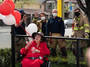 Marion Greene poses for a photo with members of the Calgary Fire Department during her on 100th birthday with her family and friends outside Extendicare Hillcrest on Saturday, May 15, 2021.