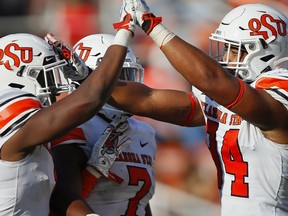 STILLWATER, OK - SEPTEMBER 26:  Linebacker Calvin Bundage #1 gets congratulated by linebacker Amen Ogbongbemiga #7 and defensive end Trace Ford #94 of the Oklahoma State Cowboys after sacking quarterback Jarret Doege of the West Virginia Mountaineers for a loss of six yards in the third quarter on September 26, 2020 at Boone Pickens Stadium in Stillwater, Oklahoma.