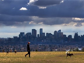 Storm clouds move in over walkers in Edworthy Park and the downtown Calgary skyline on May 4, 2021.