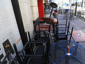 Kevin Warner with The Unicorn pub stacks patio tables and chairs on Monday, May 10, 2021. As of midnight Sunday new pandemic restrictions limit Calgary restaurants to takeout and delivery only.