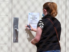 An Alberta Health Services official tapes a closed to the public sign to a door at Fairview Baptist Church on Monday, May 17, 2021. Church Pastor Tim Stephens was arrested on Sunday after repeatedly failing to comply with public health restrictions.