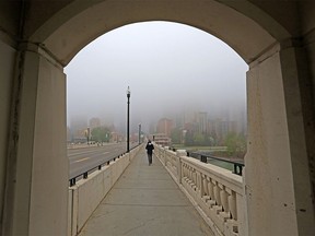 The downtown Calgary skyline is hidden by fog as a commuter crosses the Centre Street bridge on Wednesday, May 26, 2021.