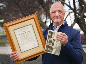 Dan Levert, professional engineer and author of On Cold Iron poses for a photo with a framed copy of the "obligation" he took to receive his iron ring.