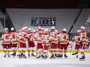 Calgary Flames players celebrate the team’s overtime win against the Vancouver Canucks at Rogers Arena in Vancouver on Sunday, May 16, 2021.