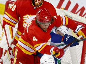 Flames defenceman Rasmus Andersson gives Vancouver Canucks winger Jayce Hawryluk a rough ride in front of the Flames net last night at the Saddledome.