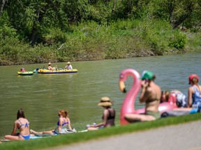 People spend the sunny afternoon along the Elbow River in Stanley Park while a heat warning is in effect in Calgary on Wednesday, June 2, 2021.