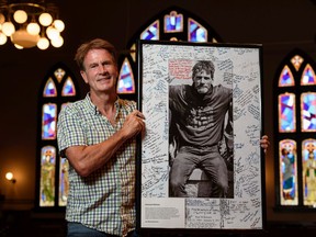 John Pentland, lead minister at Hillhurst United Church, poses for a photo with a framed photo of Paul Wilkinson signed by members of the community and participants at Wilkinson's funeral. A park along Memorial Drive N.W. is going to be named after Paul Wilkinson, who was homeless and well-known is the community of Kensington.