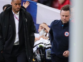 Denmark's midfielder Christian Eriksen (C) is evacuated after collapsing on the pitch during the UEFA EURO 2020 Group B football match between Denmark and Finland at the Parken Stadium in Copenhagen on June 12, 2021.