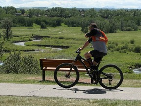 A man is seen riding his bicycle near Fish Creek during a warm afternoon in Calgary. Saturday, June 12, 2021.