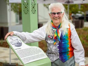 Lois Szabo poses for a photo with the plaque that has just been unveiled at the opening of the commons named after her in Calgary’s Beltline on Wednesday, July 21, 2021.