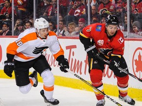 CALGARY, AB - OCTOBER 15: T.J. Brodie #7 of the Calgary Flames carries the puck against Tyler Pitlick #18 of the Philadelphia Flyers during an NHL game at Scotiabank Saddledome on October 15, 2019 in Calgary, Alberta, Canada.