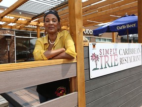 Fay Bruney poses and shows one of the boards kicked out and damaged at Simply Irie restaurant on 6 St SW in Calgary on Wednesday, July 14, 2021. The popular restaurant has seen a rise in vandalism and theft since reopening after COVID-19.