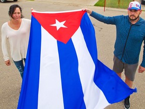 Anne Marie Harmsen and her husband Jose Gonzalez Estevez hold a Cuban flag outside their home in Chestermere on Wednesday, July 21, 2021. The Cuban-Canadian family is part of local protests calling for democracy and an end to dictatorship in Cuba.